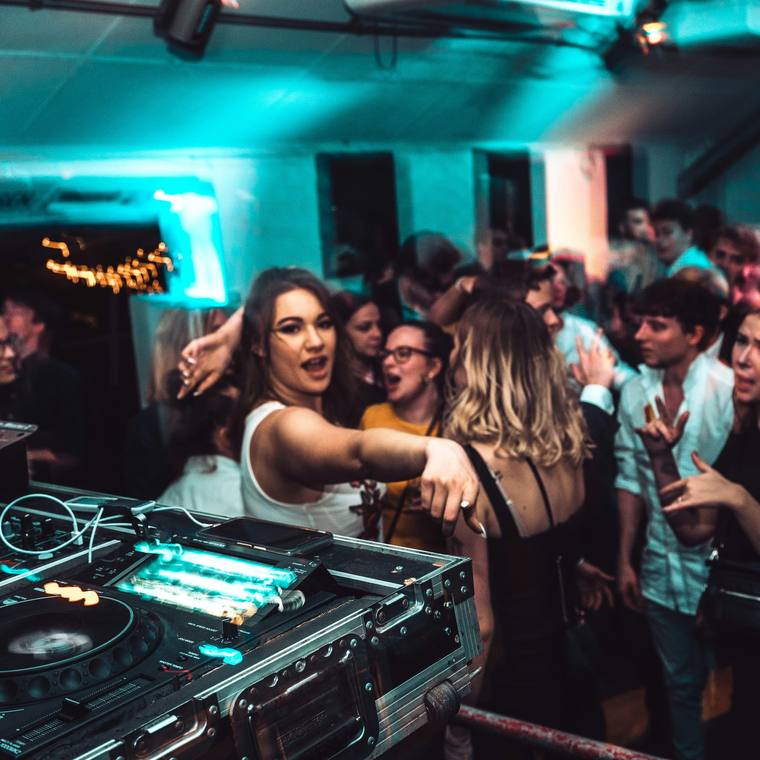 Fiesta en un club con la cabina del DJ en primer plano