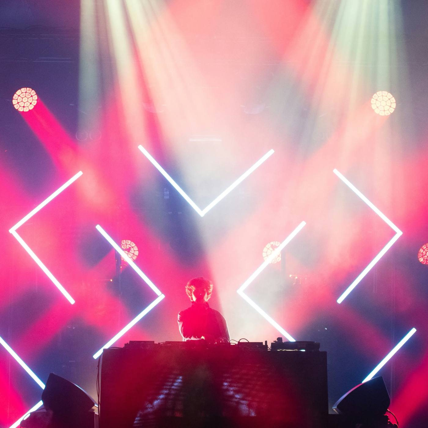 DJ en un escenario con láseres rosas